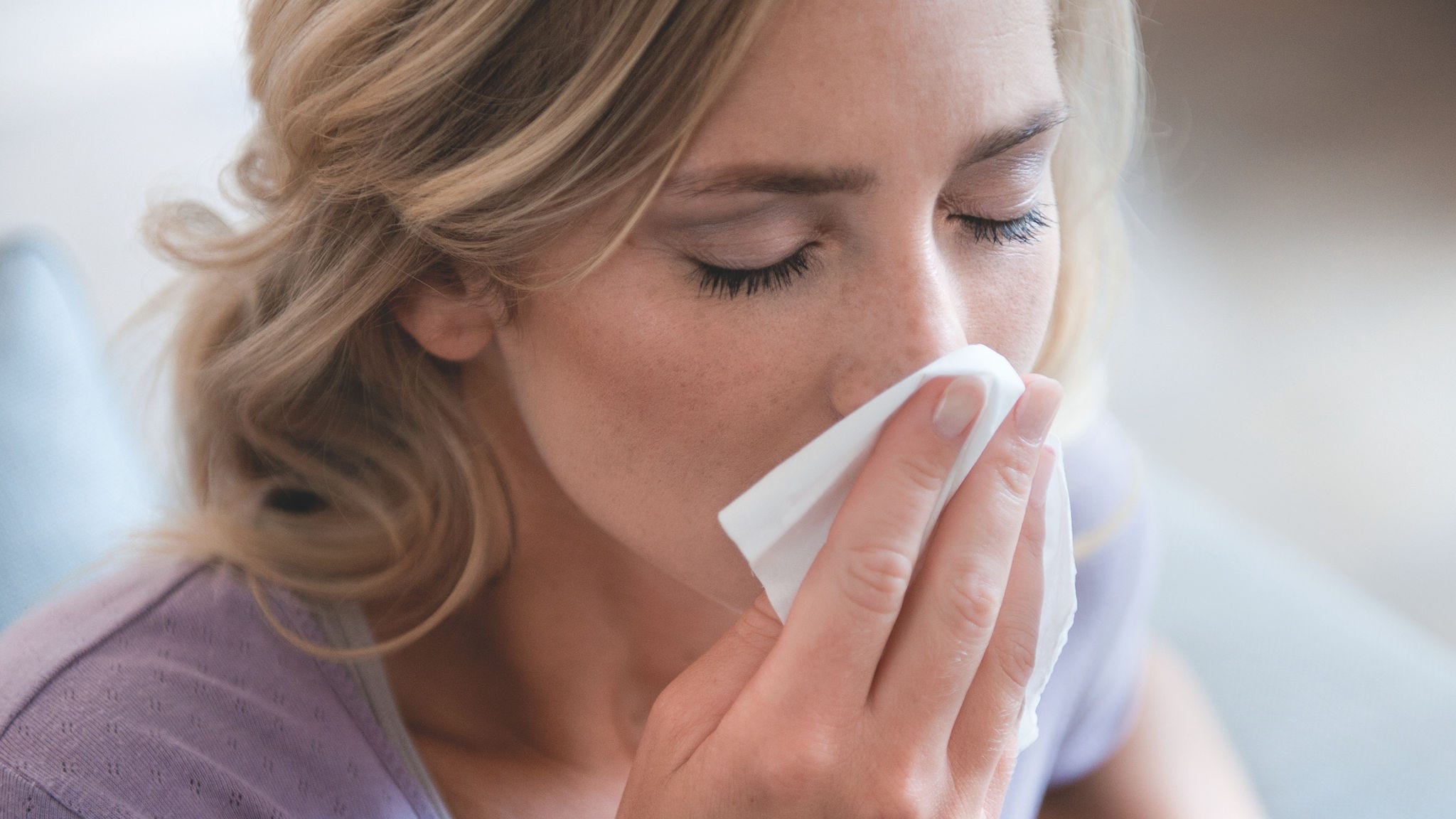 Žena ispuhuje nos zbog alergije na pelud