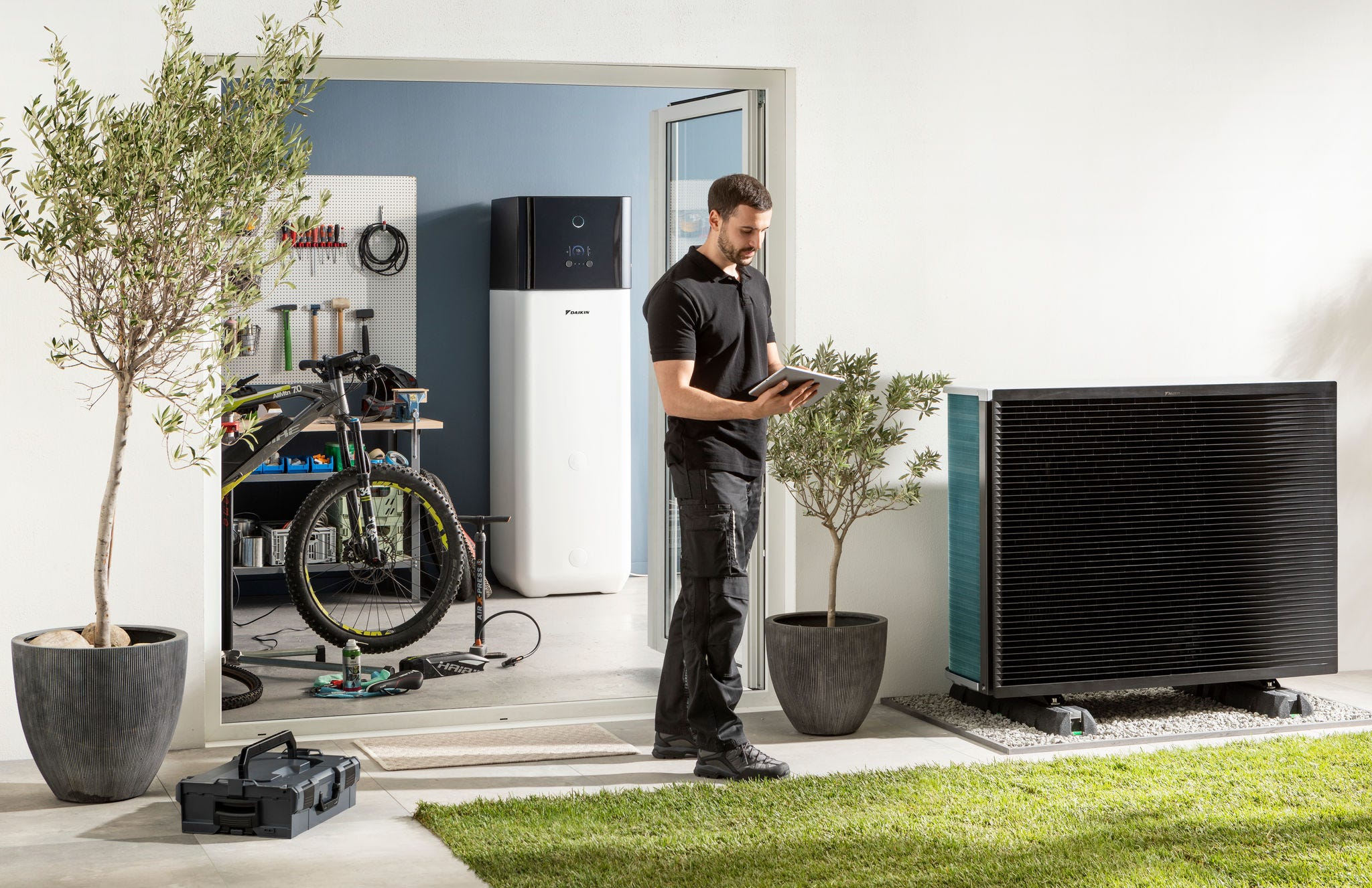 Instalater provjerava vanjsku jedinicu dizalice topline zrak-voda i spremnik za toplu vodu