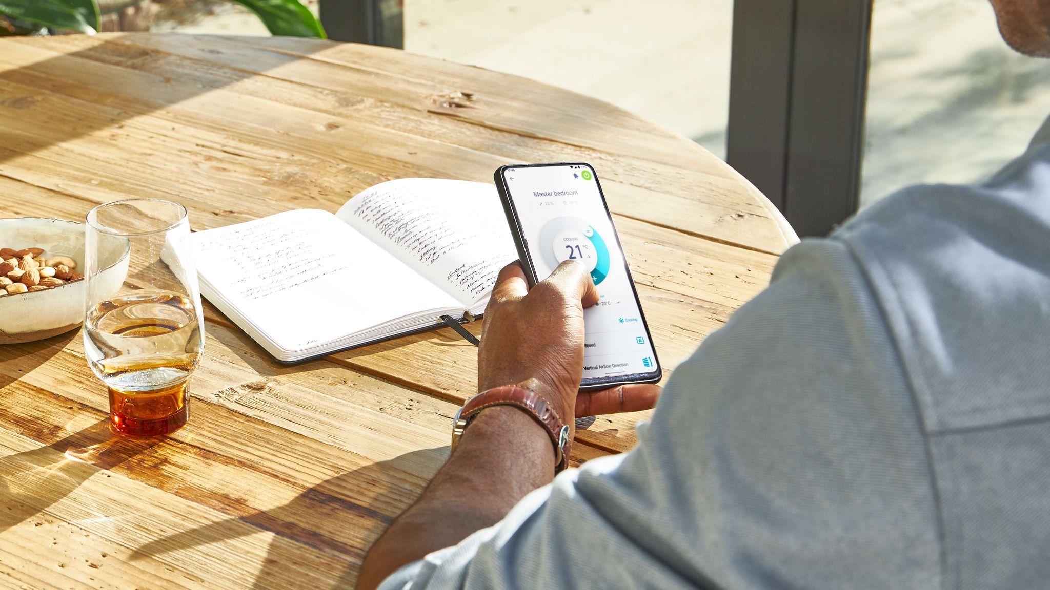 Muškarac upravlja temperaturom u svom domu s bilo kojeg mjesta uz Daikin aplikaciju Onecta na pametnom telefonu