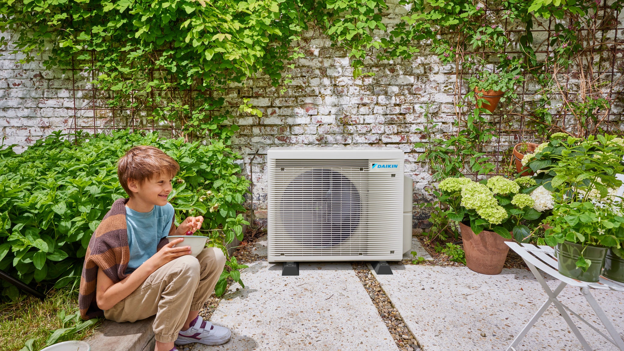 Dijete blizu unutarnje jedinice Daikin hibridne dizalice topline, spoj energetske učinkovitosti i lijepog vrtnog okruženja