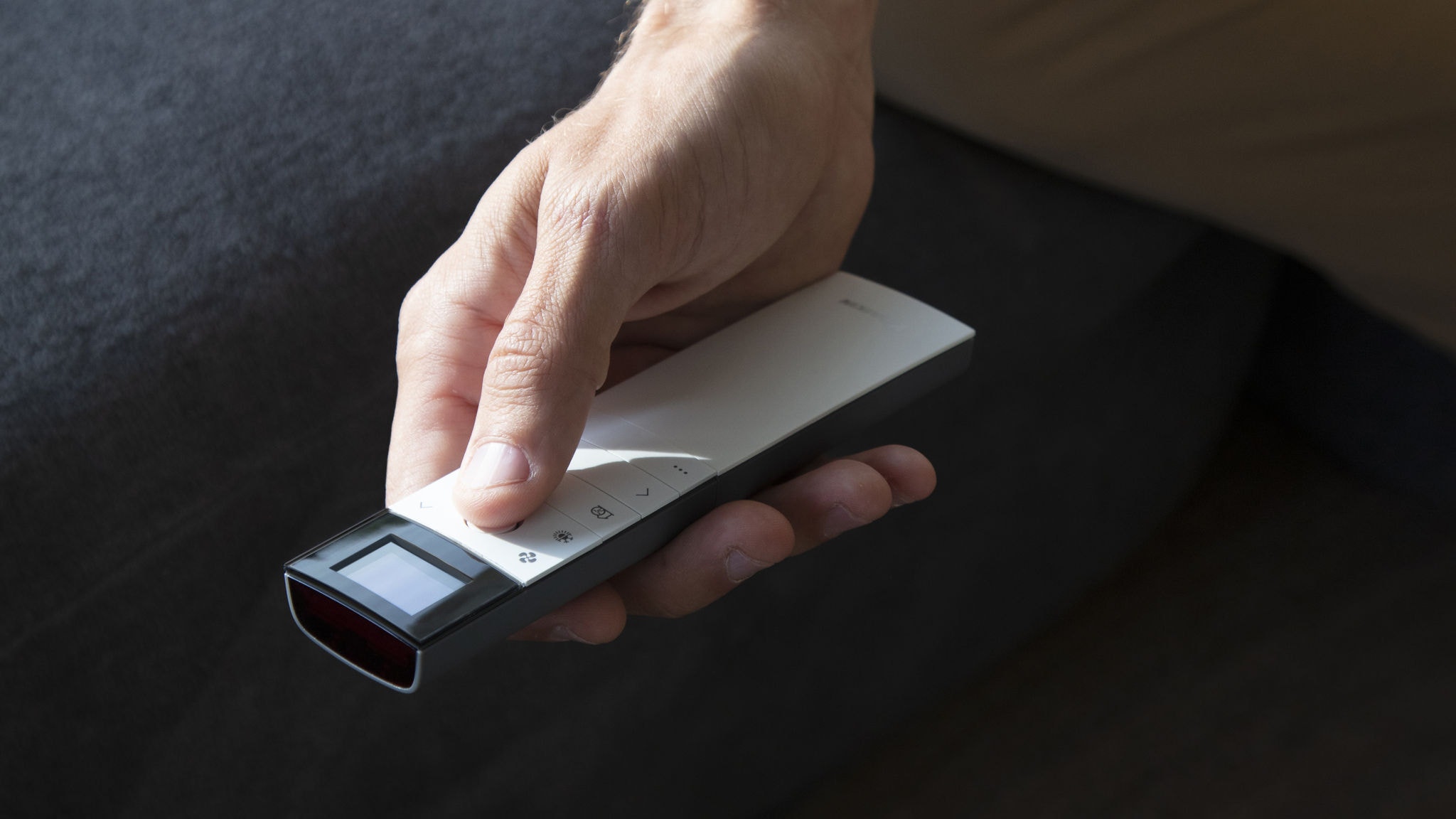 Muškarac upravlja svojim klima-uređajem u dnevnoj sobi putem daljinskog upravljača