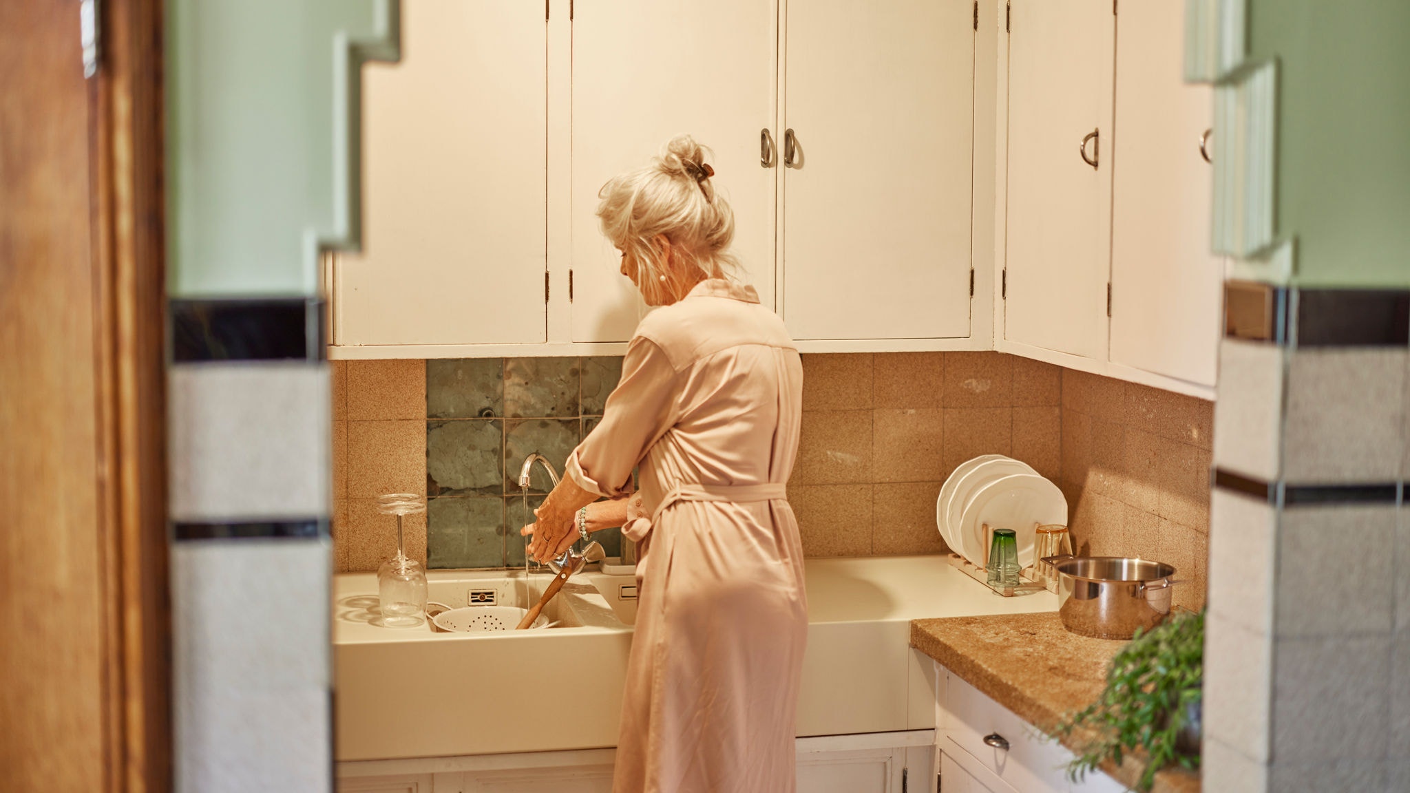 Žena pere suđe potrošnom toplom vodom iz Multi Split sustava