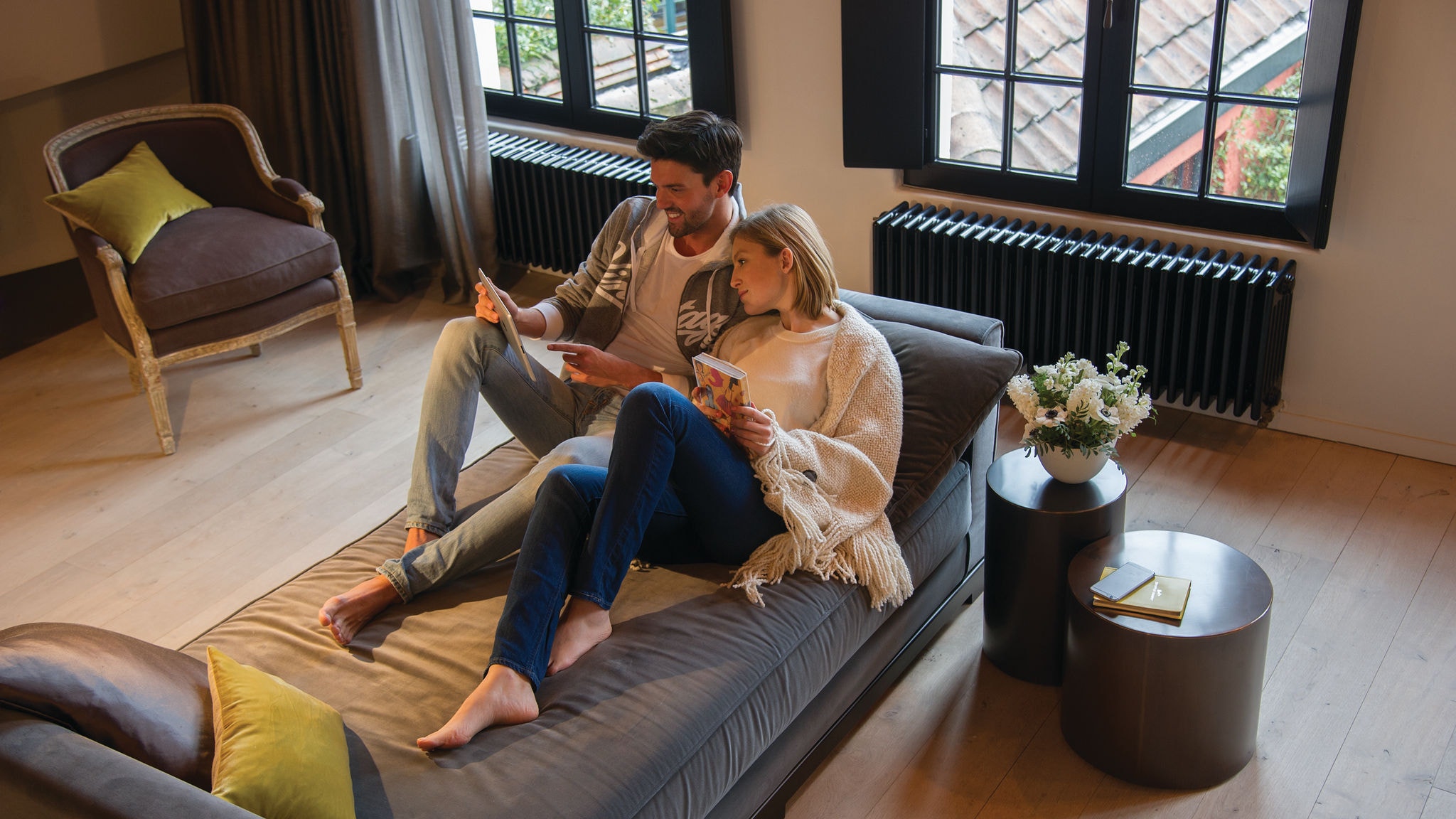 Par koji se opušta na sofi i surfa na tablet uređaju