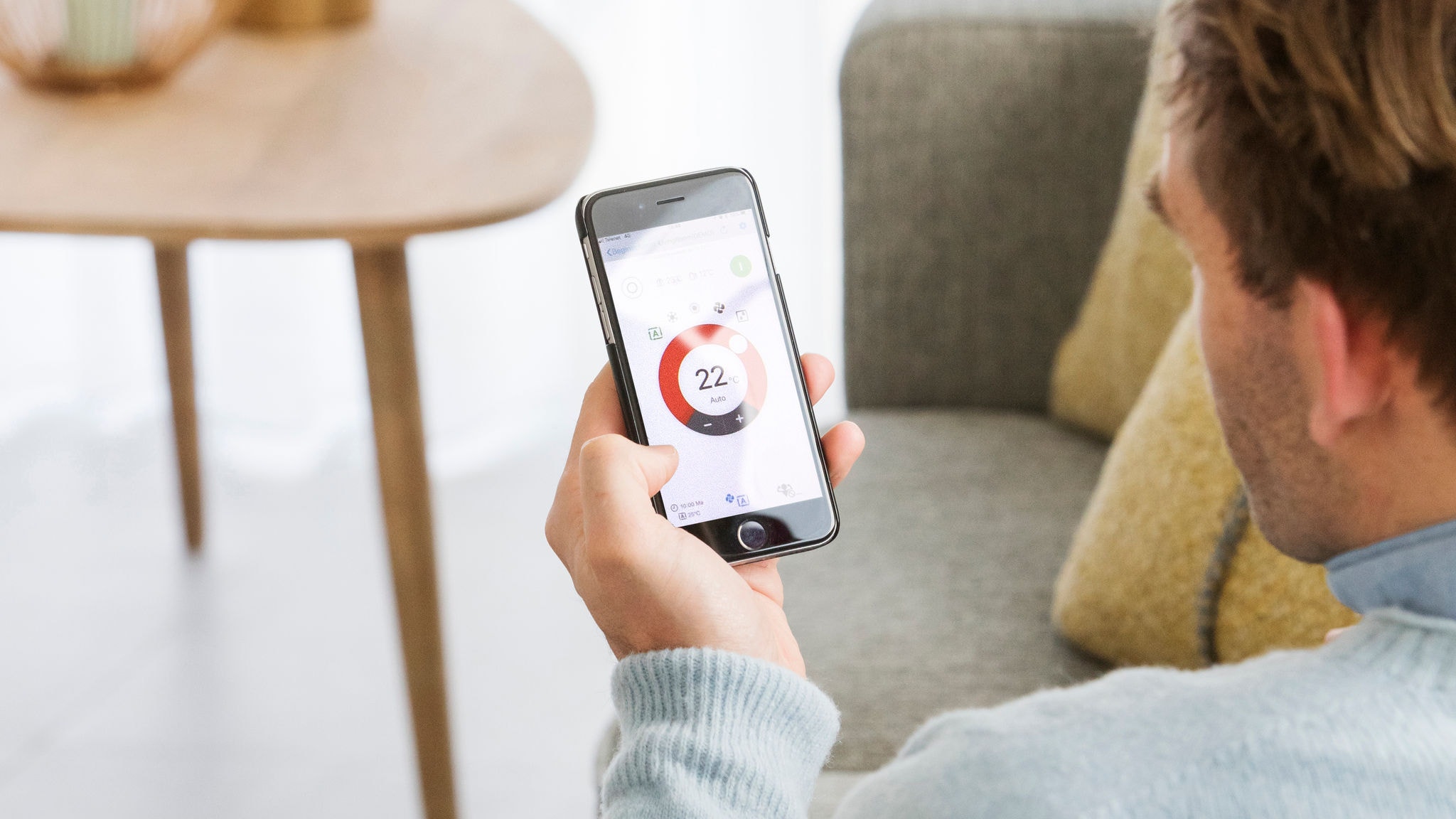 Muškarac koji upravlja sustavom grijanja putem Daikin aplikacije Onecta