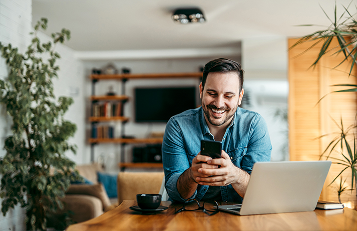 Muškarac gleda u svoj mobitel u svom domu